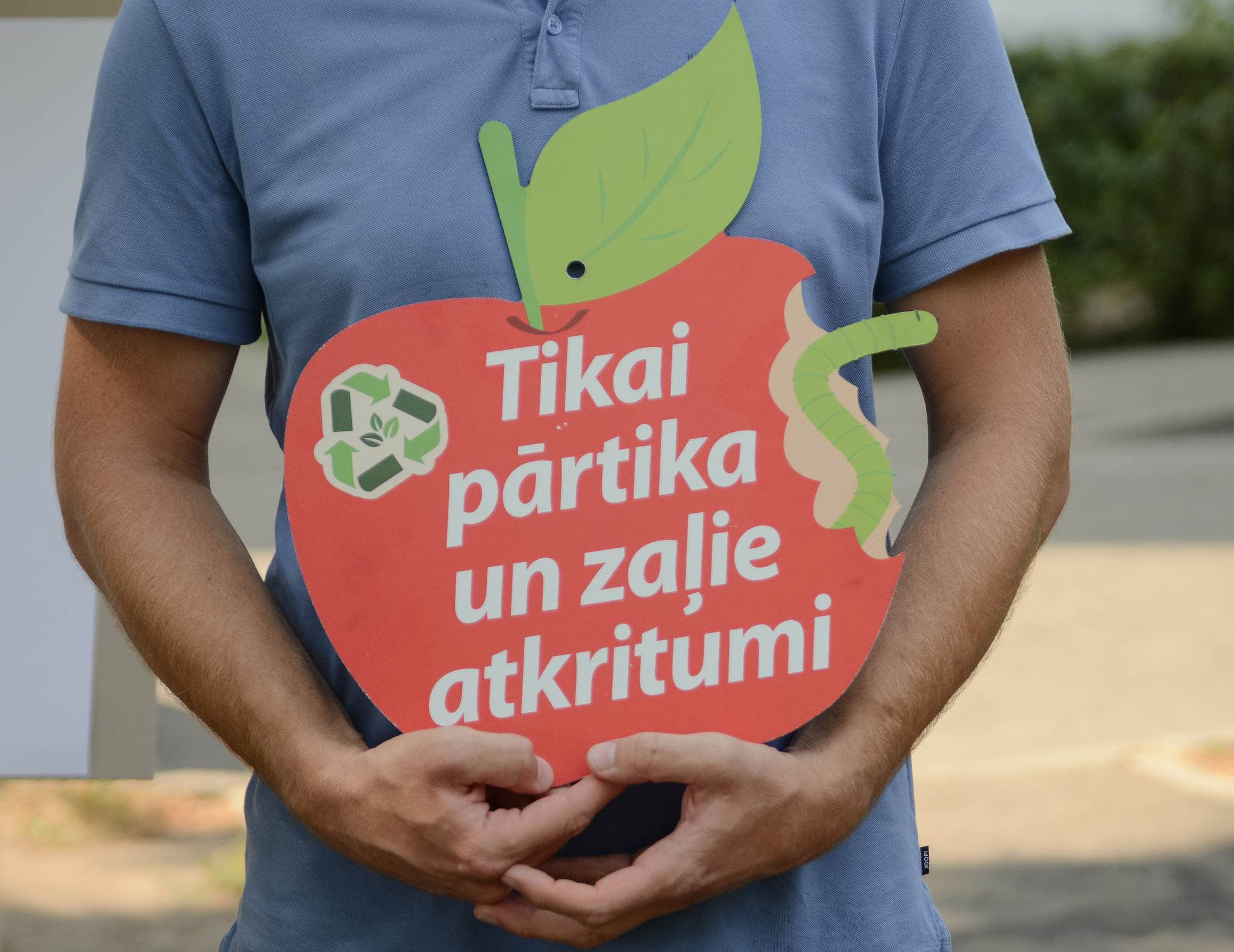 Cilvēks tur zīmi ar uzrakstu 'Tikai pārtika un zaļie atkritumi'