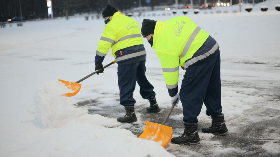 Vīrieši ar lāpstām tīra sniegu