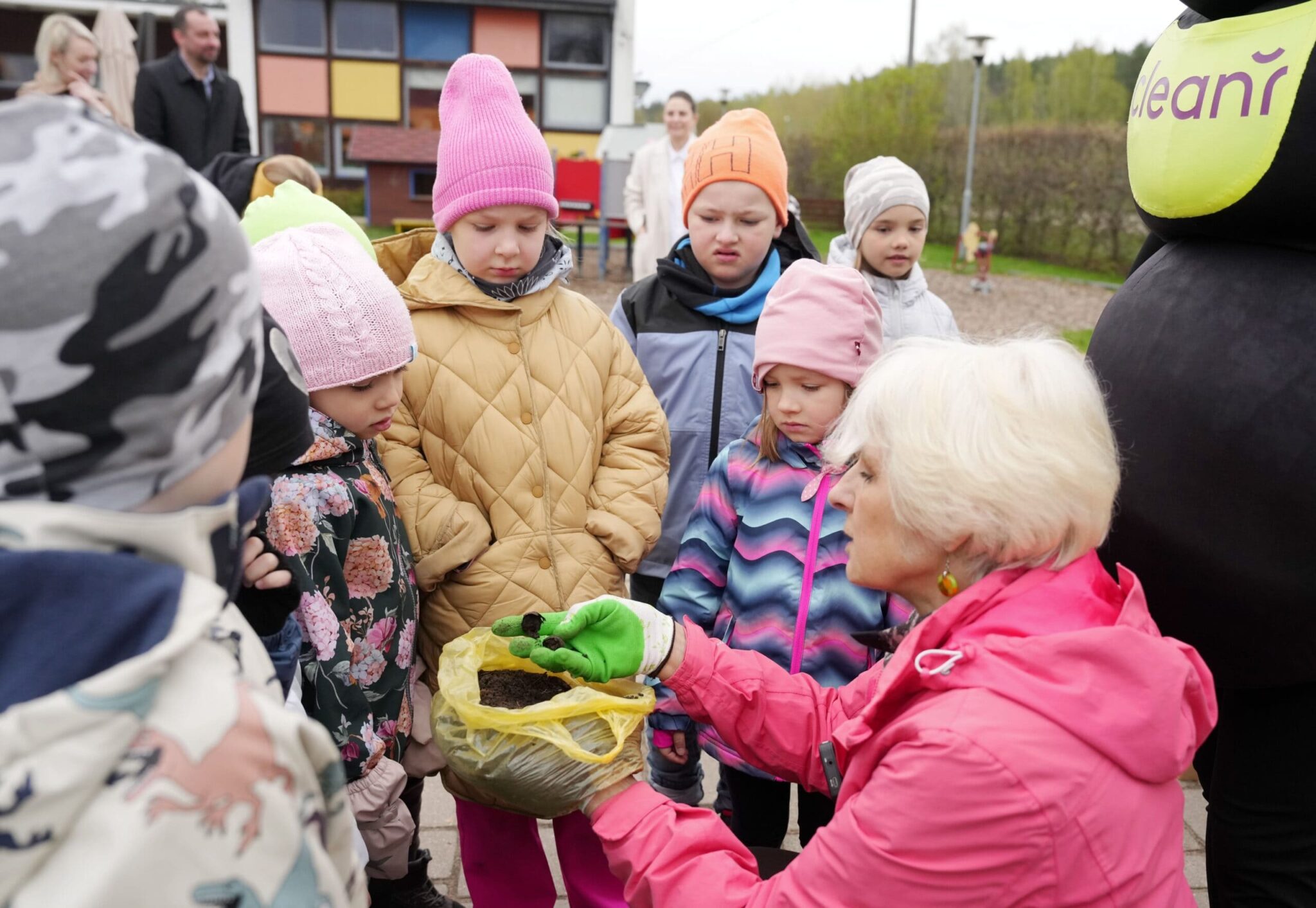 Sieviete bērniem rāda komposta zemi
