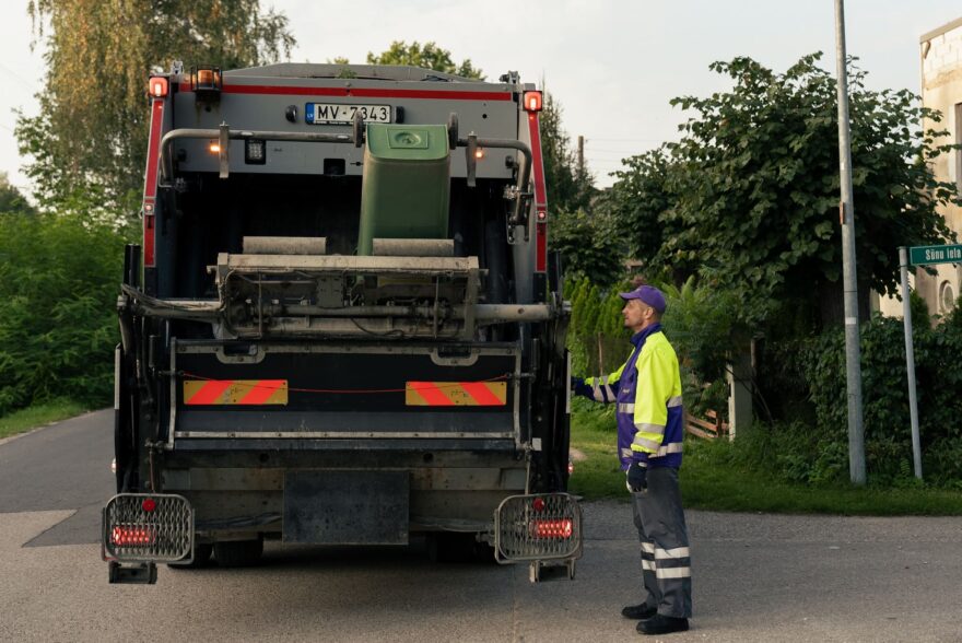 Darbinieks iztukšo sadzīves atkritumu konteineru