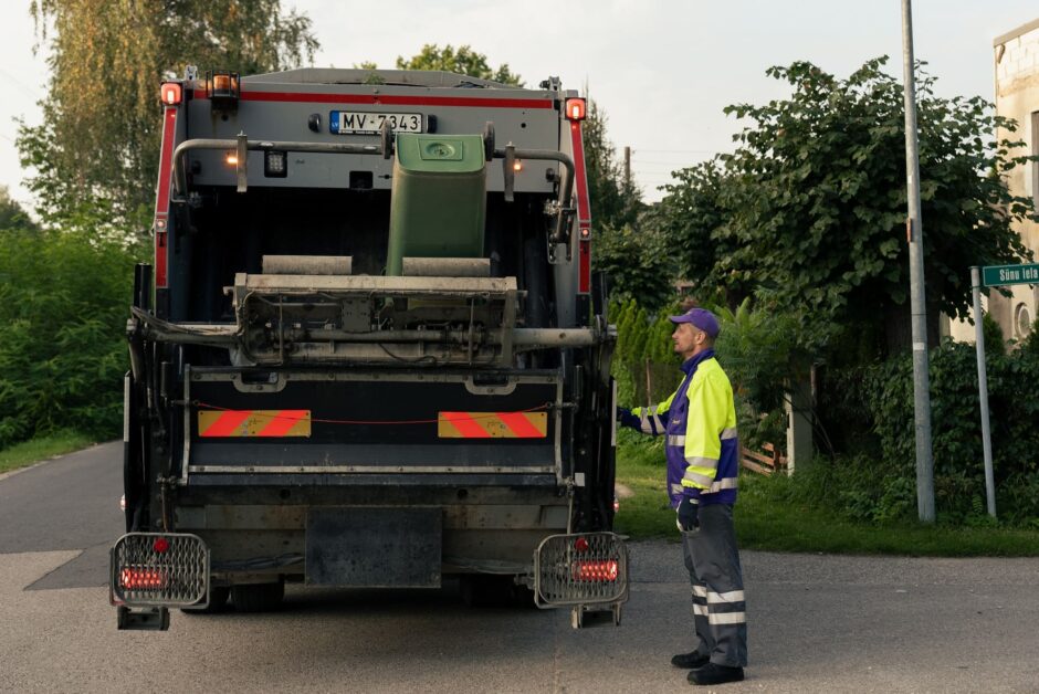 Darbinieks iztukšo sadzīves atkritumu konteineru